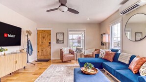 A living room with a blue sofa, wooden floor, and a flat-screen TV. - Downtown Redmond 4BR Walk to Food & Brews (Redmond)