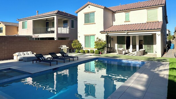 A residential property with a swimming pool, outdoor seating, and a two-story building with balconies. - Luxury Modern Retreat with Pool & Spa – Near the Strip (Las Vegas)