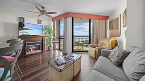 Ein Wohnzimmer mit Flachbildfernseher, Kamin, Sofa, Couchtisch und einem Balkon mit Blick.