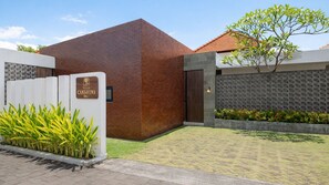 Eine moderne Villa mit Backsteinfassade, geschlossenem Eingangstor und einem gepflegten Garten.