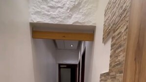 Un couloir étroit avec un lave-linge, un panneau mural en bois et un plafond à la finition texturée.