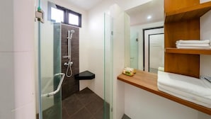 Un baño moderno con cabina de ducha de vidrio, tocador de madera y espejo.