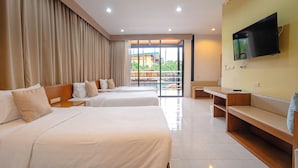 Habitación de hotel con dos camas, televisión, balcón con vistas y zona de estar.