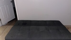A dark grey sofa in a room with a white door and tiled floor. - Cozy 1-bedroom studio in quaint Belleville with AC and gym access (Belleville)