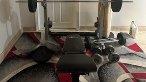 A home gym with a bench press, barbell, and weight plates. - Cozy 1-bedroom studio in quaint Belleville with AC and gym access (Belleville)