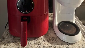 A red coffee maker and a white coffee pot on a kitchen counter. - Cozy 1-bedroom studio in quaint Belleville with AC and gym access (Belleville)