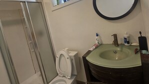A bathroom with a toilet, a sink, a shower, and a window. - Cozy 1-bedroom studio in quaint Belleville with AC and gym access (Belleville)