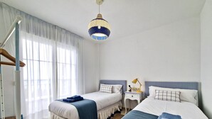 Ein Hotelzimmer mit zwei Betten, einem Nachttisch mit Lampe, einer Hängelampe und einer Treppe.
