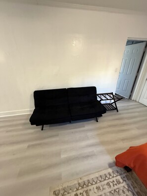 A room with a black sofa, a small wooden table, and a patterned rug. - 116 YARDS FROM THE BEACH (Deerfield Beach)