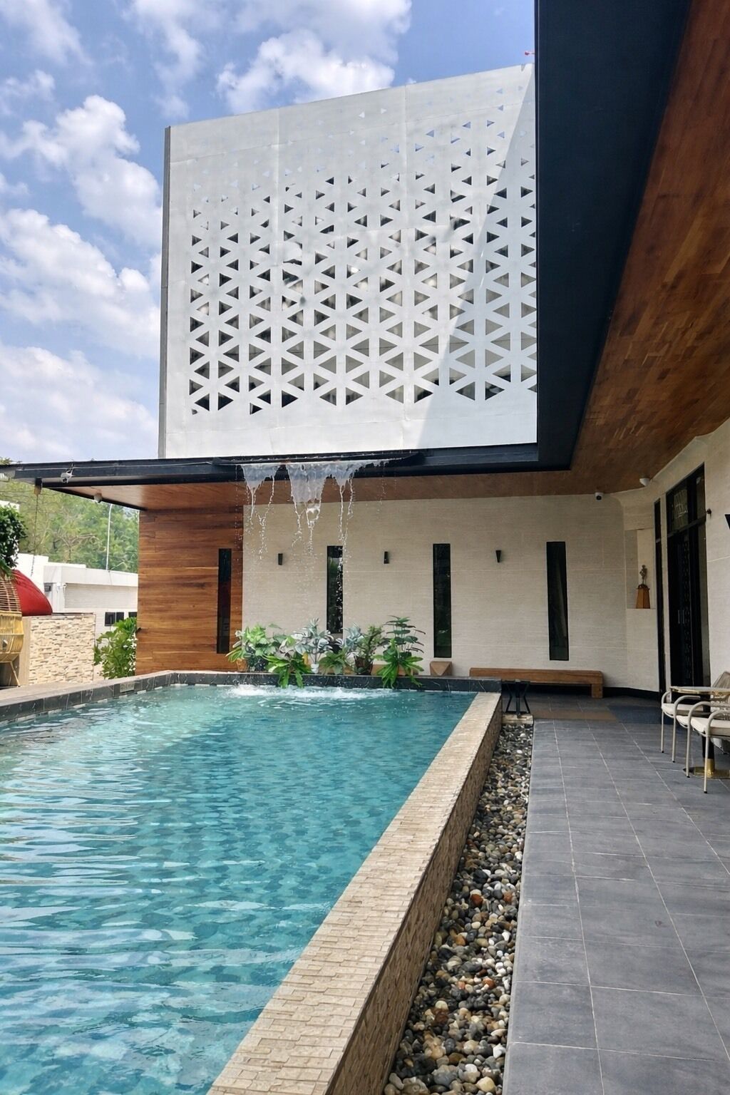 A modern outdoor pool area with a clear pool, a wooden deck, and a white lattice structure.