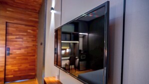 Un intérieur moderne avec un téléviseur à écran plat fixé au mur, un plancher en bois et un banc.