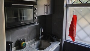 Eine Küche mit einer Kombi-Mikrowelle, einem Spülbecken und Schränken.