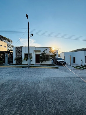 Un edificio moderno con techo plano, un garaje y un coche estacionado.
