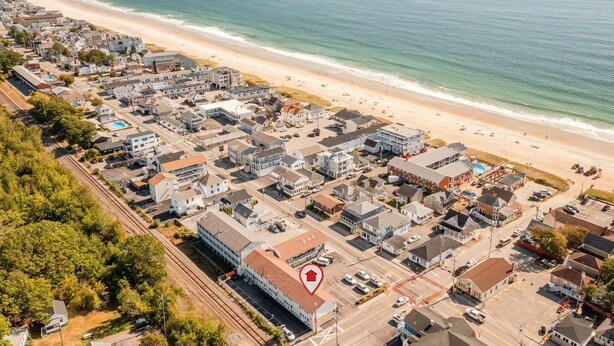Vue aérienne d’une ville côtière avec une plage, des immeubles résidentiels et une gare.