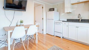 Une cuisine moderne avec des meubles blancs, un téléviseur à écran plat, un four à micro-ondes, un réfrigérateur, un four et un évier.