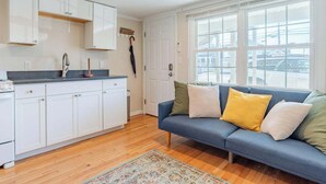 Une cuisine moderne avec des meubles blancs, un évier et une fenêtre donnant sur la rue.