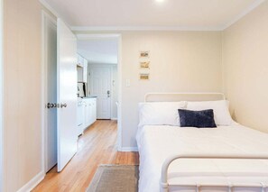 Ein Schlafzimmer mit einem Bett, einem kleinen Teppich und einer Küchenzeile im Hintergrund.
