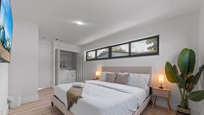 Un dormitorio con una cama grande, lámparas de noche, una ventana con vistas y una planta en maceta.