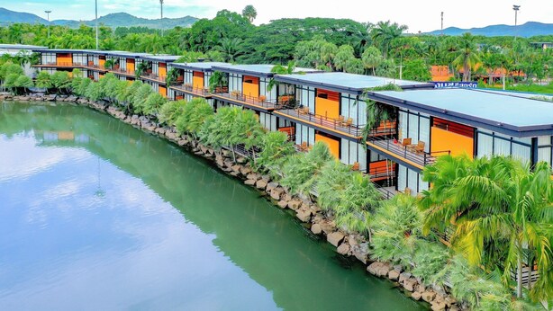A modern hotel with a series of rooms along a riverbank, featuring balconies and a view of the water. - Nongnooch Lakeside Pattaya (Sattahip)
