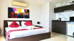 A hotel room with a bed, a painting, an air conditioner, a kitchen area with a sink and stove, and a marble backsplash. - Patong Beach Walking Street Seaview C257 (Patong)
