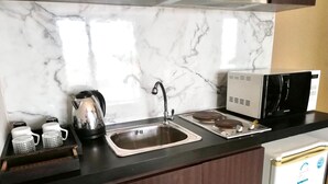 A kitchen with a marble backsplash, a stainless steel sink, a kettle, a microwave, and a refrigerator. - Patong Beach Walking Street Seaview C257 (Patong)