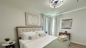 A bedroom with a bed, a bedside table with a plant, a nightstand, and a ceiling fan. - Casa Legacy house — 8 Min Walk to AT&T Stadium, Sleeps 10 (Arlington)