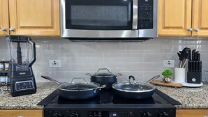 A kitchen with a stainless steel microwave, a gas stove, a blender, and various kitchen utensils. - Casa Legacy house — 8 Min Walk to AT&T Stadium, Sleeps 10 (Arlington)