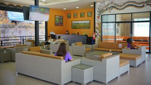 A hotel lobby with seating areas, a reception desk, and artwork on the walls. - Nongnooch Boutique Resort (Sattahip)
