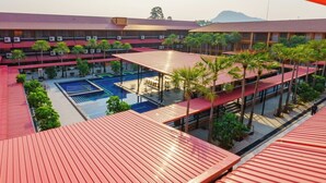 A hotel with multiple swimming pools, covered outdoor seating areas, and a mountainous backdrop. - Nongnooch Boutique Resort (Sattahip)