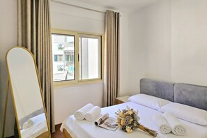 Ein Hotelzimmer mit Bett, Spiegel, Fenster und Blick nach draußen.