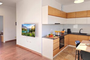Eine moderne Küche mit Holzausstattung, einem Einbauofen und einem Essbereich mit Tisch und Stühlen.