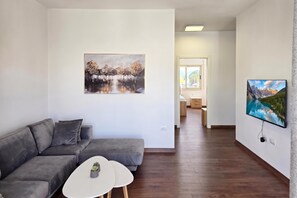 Ein modernes Wohnzimmer mit einem grauen Sofa, einem kleinen weißen Tisch und zwei Bildern an den Wänden.