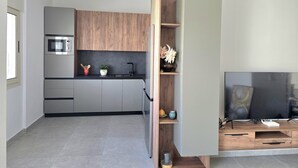 Una cocina moderna con armarios grises, un microondas integrado y una estantería de madera.