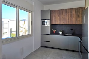 Eine Küche mit integriertem Mikrowellenherd, Holzschränken, einer schwarzen Arbeitsplatte und einem Fenster mit Außenblick.