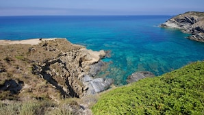 A coastal landscape with clear blue sea, rocky cliffs, and sparse vegetation. - Residence Argentiera Room 22 Sea View, Miniera dell’Argentiera, Italy (Miniera dell’Argentiera)