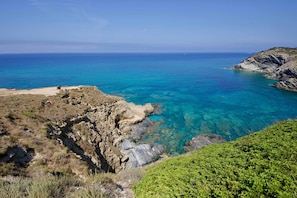 A coastal landscape with clear blue sea, rocky cliffs, and sparse vegetation. - Residence Argentiera Room 22 Sea View, Miniera dell’Argentiera, Italy (Miniera dell’Argentiera)