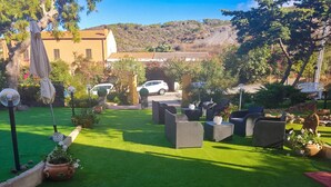 A patio area with outdoor furniture, a car, and a building in the background. - Residence Argentiera Room 22 Sea View, Miniera dell’Argentiera, Italy (Miniera dell’Argentiera)