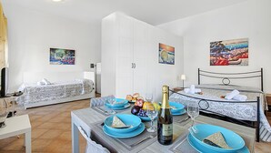 Een hotelkamer met een eettafel gedekt voor twee personen, een bed met uitzicht en een kledingkast.