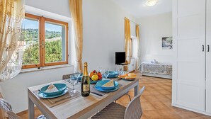 Een eetgedeelte met een tafel gedekt voor twee personen, een champagnefles en een fruitschaal.
