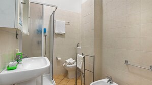 A bathroom with two sinks, a toilet, a shower, and a towel rack.