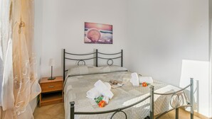 A bedroom with a bed, a nightstand, a painting of a shell, and a window. - Residence Argentiera Studio 8 Sea View, Miniera dell’Argentiera, Italy (Miniera dell’Argentiera)