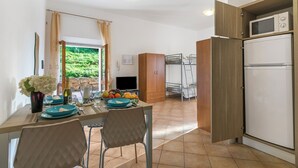 A kitchen with a dining table set, a refrigerator, and a television. - Residence Argentiera Studio 8 Sea View, Miniera dell’Argentiera, Italy (Miniera dell’Argentiera)
