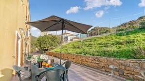 A patio with a table, chairs, and an umbrella. - Residence Argentiera Studio 8 Sea View, Miniera dell’Argentiera, Italy (Miniera dell’Argentiera)