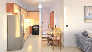 A compact kitchen with a refrigerator, oven, and wooden cabinets. - Mandalay Suites By The Beach 079, Durres, Albania (Durres)