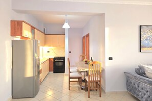 Eine kleine Küche mit Kühlschrank, Backofen und Holzschränken.