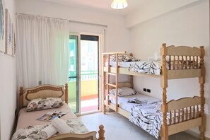 A room with a single bed, a bunk bed, a window with curtains, and a door leading to an outdoor area. - Mandalay Suites By The Beach 079, Durres, Albania (Durres)
