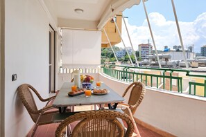 A balcony with a table set for breakfast, wicker chairs, and a view of the cityscape. - Mandalay Suites By The Beach 079, Durres, Albania (Durres)
