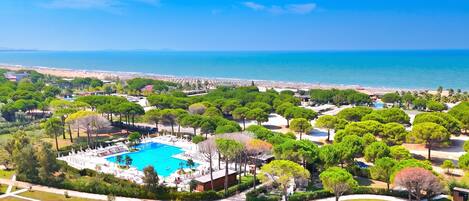 A resort with a swimming pool, landscaped gardens, and a beach view.