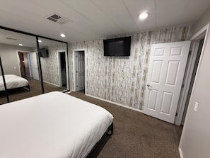 A bedroom with a bed, a mirror, a television, and a door. - Sedona Retreat Walk to Park, Hikes & Sunset Views (Sedona)