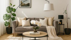 Ein Wohnzimmer mit einer Couch, einem Couchtisch, einer Lampe und Topfpflanzen.